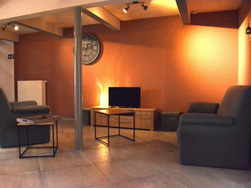 uma sala de estar com duas cadeiras e uma televisão em Vintage Holiday Home in Couvin near River em Aublain