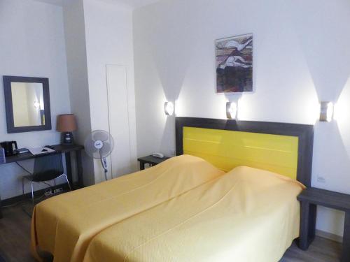 a bedroom with a yellow bed and a mirror at Hôtel Restaurant Aux Deux Roses in Neuf-Brisach