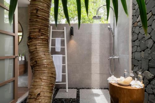 a bathroom with a palm tree in the shower at The Sarojin in Khao Lak