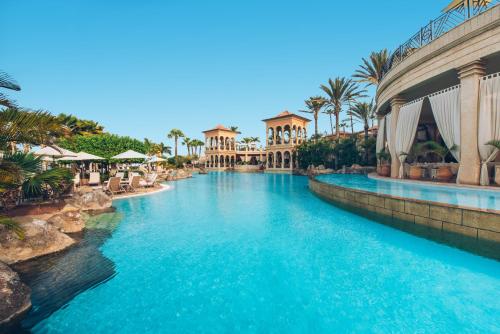 a pool at a resort with blue water and palm trees at JOIA El Mirador by Iberostar -Adults Only in Adeje