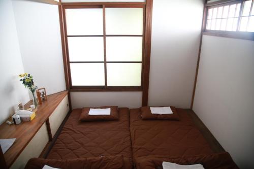 都留市にあるゲストハウスゆかりのベッドと窓が備わる小さな客室です。