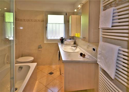 a bathroom with a sink and a toilet and a tub at Apartment Larjëi in Ortisei