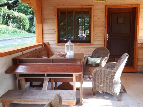 a wooden table and chairs on the porch of a cabin at Tidy furnished apartment, located in a wooded area in Schönecken