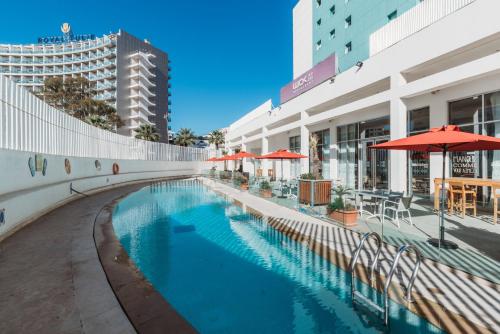 a swimming pool with red umbrellas next to a building at Ibis Tanger City Center in Tangier