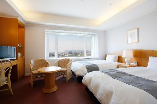 a hotel room with two beds and a window at Hotel Kyocera in Kirishima