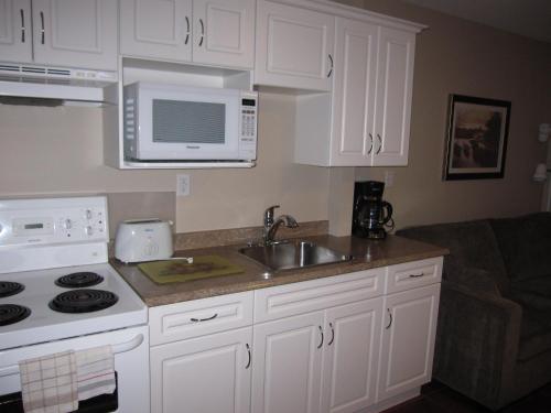 a kitchen with white cabinets and a sink and a microwave at Sandy Beach Suites in Osoyoos