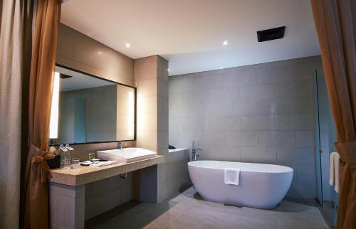 y baño con bañera, lavabo y espejo. en Kyriad Hotel Muraya Aceh en Banda Aceh