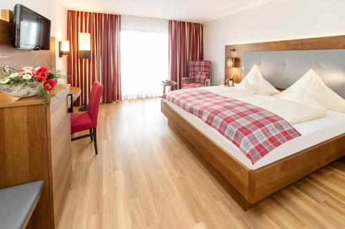 a hotel room with a large bed and a desk at SeeHotel Wassermann in Seebruck