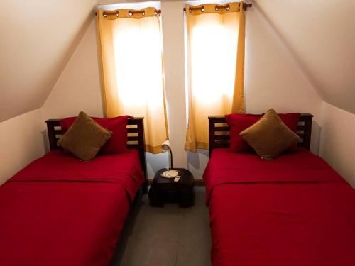 two beds in a room with red pillows at Hibiscus Cottage in Ban Dan Kao