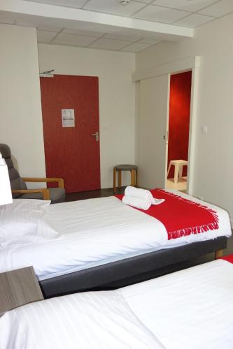 two beds in a room with a red door at Hostellerie Bon Pasteur in Angers