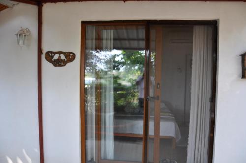 a glass door to a room with a bed at KUŞ YUVASI PANSiYON in Cıralı