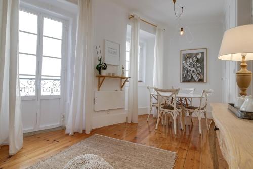 a white living room with a table and chairs at Madragoa Cosy Apartment in Lisbon