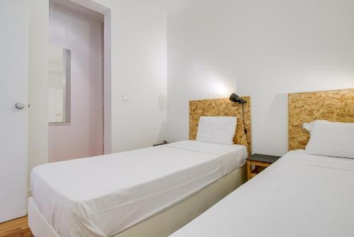 two beds in a room with white walls at Madragoa Cosy Apartment in Lisbon