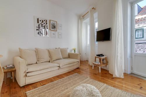 a white living room with a couch and a tv at Madragoa Cosy Apartment in Lisbon