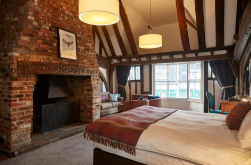 a bedroom with a brick fireplace and a bed at White Hart Hotel by Greene King Inns in Coggeshall