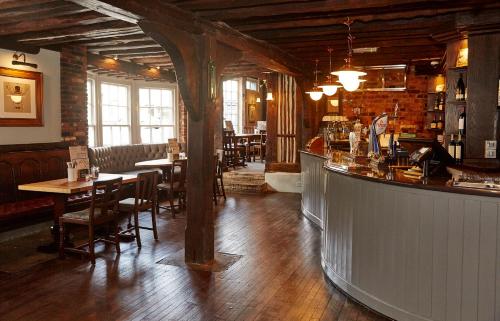 un bar dans un restaurant avec des tables et des chaises dans l'établissement White Hart Hotel by Greene King Inns, à Coggeshall