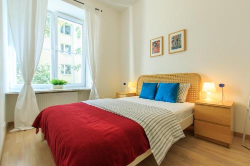 a bedroom with a bed with a red blanket and blue pillows at Rental Apartments Wilcza in Warsaw