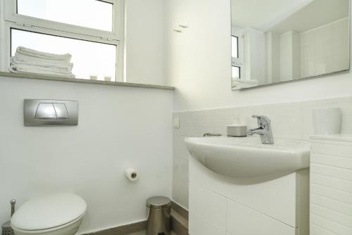 a white bathroom with a toilet and a sink at the coolest loft and terrace-varkiza sea view in Varkiza