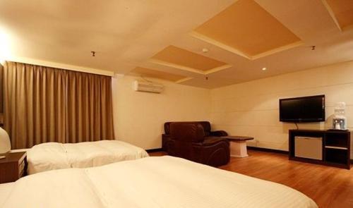 a hotel room with a bed and a chair and a television at Zaw Jung Business Hotel in Taichung