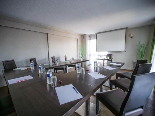 a conference room with tables and chairs and a screen at Hôtel Inn Design Resto Novo Langres in Langres