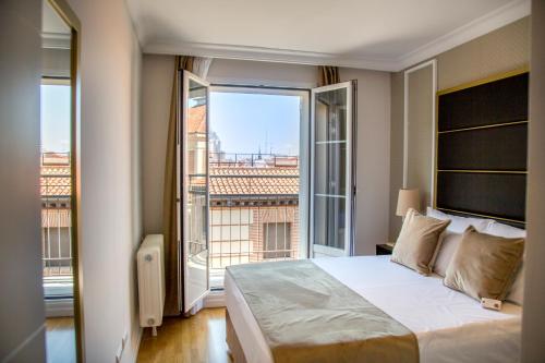 Un dormitorio con una cama grande y una ventana grande. en TGH Gran Vía Apartments, en Madrid