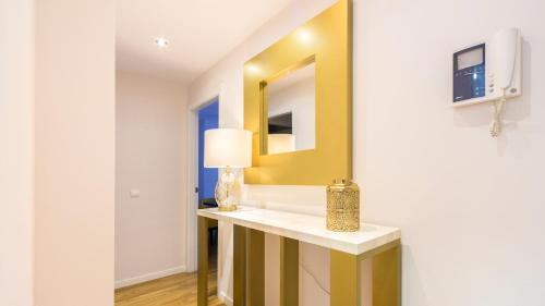 Habitación con mesa, lámpara y espejo. en TGH Gran Vía Apartments, en Madrid