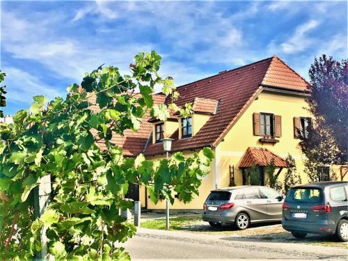 a yellow house with cars parked in front of it at Landhaus Weinblick in Rohrendorf bei Krems