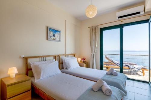 two beds in a room with a view of the ocean at Kissakas Villas in Leonidion