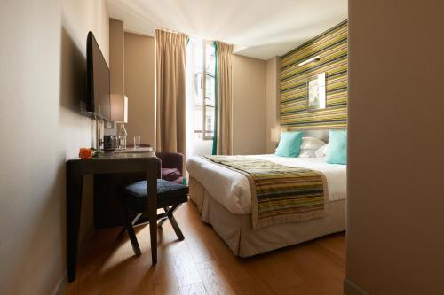 a bedroom with a bed, desk, chair, and window at Le Mathurin Hotel & Spa in Paris