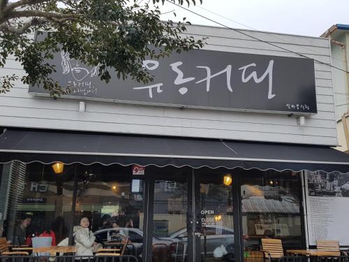 a restaurant with a sign on the side of a building at Gudeok Guesthouse in Seogwipo