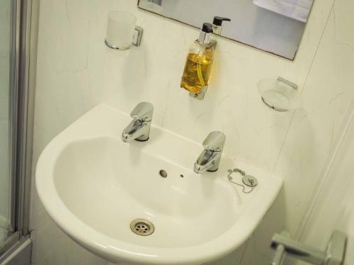 a white sink in a bathroom with a mirror at The Derby Hotel in Barrow in Furness