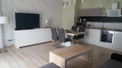 eine Küche mit einem Tisch und Stühlen sowie einem TV in der Unterkunft Wrocław APARTAMENTY KĘPA MIESZCZAŃSKA in Breslau