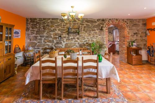 a dining room with a table and a stone wall at Casa La Escuela in Tuilla