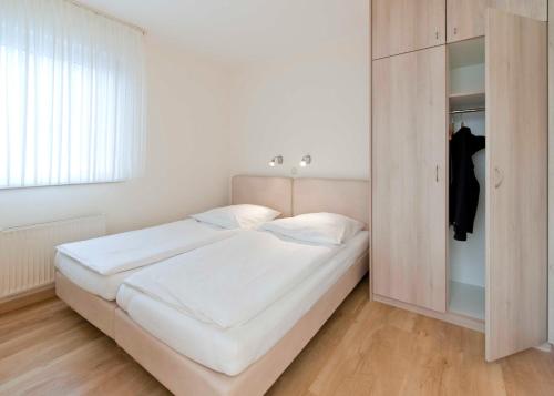 クックスハーフェンにあるHaus Seemuschel _ Fewo 5の白いベッドルーム(ベッド1台、クローゼット付)