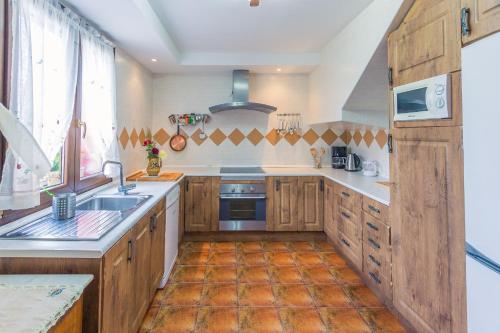 a large kitchen with wooden cabinets and a sink at Casa La Escuela in Tuilla