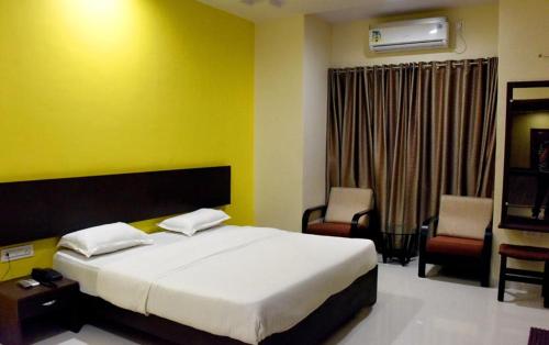 1 Schlafzimmer mit einem großen Bett und 2 Stühlen in der Unterkunft Hotel Varenya Inn in Yavatmāl
