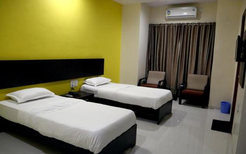 ein Hotelzimmer mit 2 Betten und einem Stuhl in der Unterkunft Hotel Varenya Inn in Yavatmāl