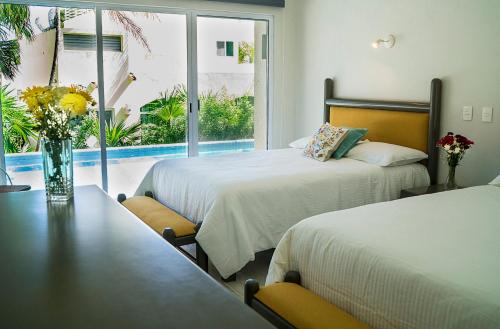a hotel room with two beds and a table and a window at 3BR Home, Steps from Spectacular Beach, Private Pool in Playa del Carmen