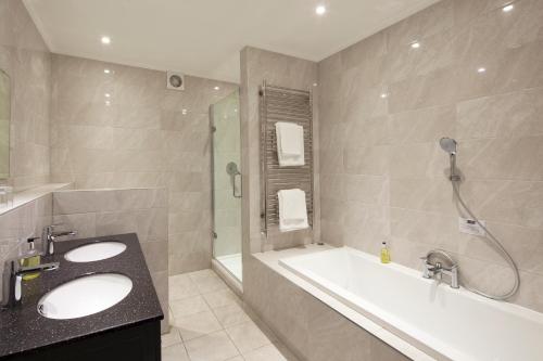 a bathroom with a tub and a sink and a shower at Elfordleigh Hotel in Plymouth