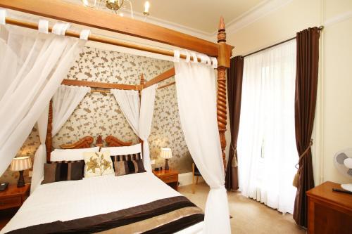 a bedroom with a canopy bed with white curtains at Woodlands Hotel, BW Signature Collection in Dundee