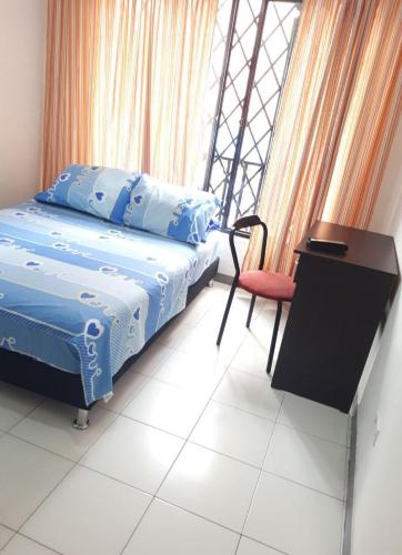 a bedroom with a bed and a desk and a chair at HOSPEDAJE VALLE DEL LILI in Cali