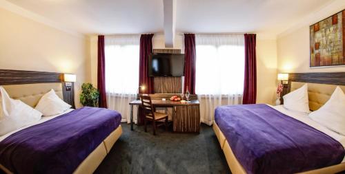 a hotel room with two beds and a desk at Hotel Famosa in Düsseldorf