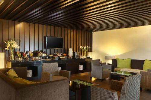 a living room with a couch and chairs and a television at Hotel Santika Bogor in Bogor