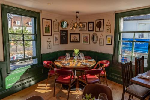 a dining room with a table and chairs and windows at Albert Arms in Esher