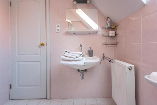 a pink bathroom with a sink and a mirror at Flora Villa in Hévíz