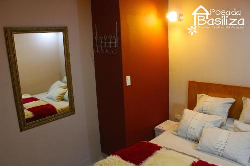 1 dormitorio con espejo junto a la cama en Posada Basiliza, Encarnación PY, en Encarnación