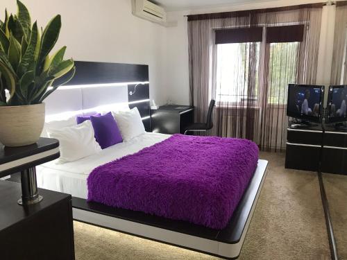 a bedroom with a purple bed and a tv at SPA Hotel in Vorzelʼ