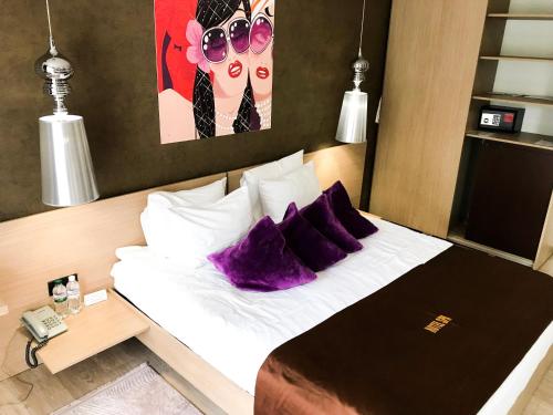 a bedroom with a bed with purple pillows and a phone at SPA Hotel in Vorzelʼ