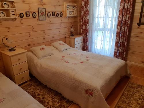 a bedroom with a bed and a window at Aleksandrówka - Domek Anastazja in Trześcianka