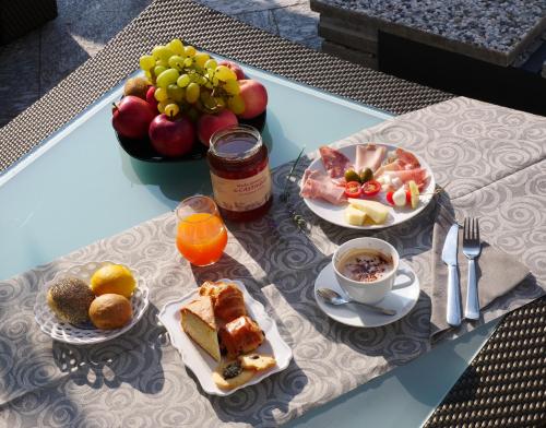 a table with plates of food and a bowl of fruit at Hotel Al Campanile - Luxury Suites & Apartments in Baveno